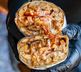 Burgeritto halves showing melted cheese, tomato and fries filling
