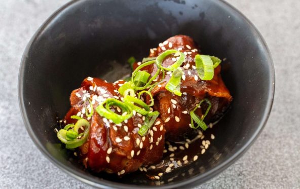Glazed rib bite garnished with sesame seeds and spring onion