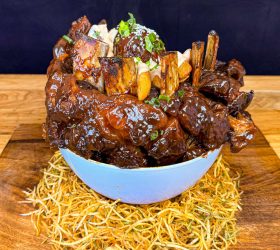 Dragon Egg glazed ribs served in a blue bowl over crispy noodles