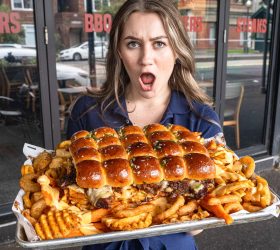 Guest holding The Slab, a tray of slider buns over loaded fries