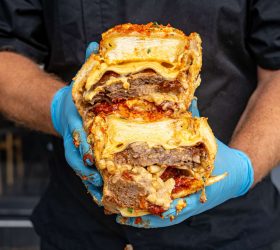 Crumbed sandwich stack with melted cheese and meat filling, held up