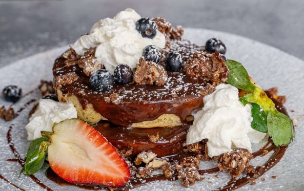 Stacked chocolate dessert with whipped cream, blueberries and strawberry