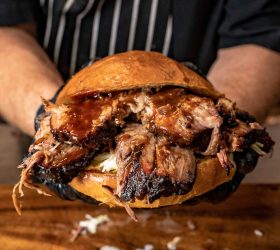 Chef holding the Oh Daddy Burger overflowing with brisket and sauce
