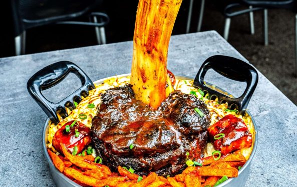 Thor's Hammer whole smoked beef shin standing in loaded cheesy fries