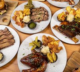 Overhead view of shared BBQ plates including ribs and sliders