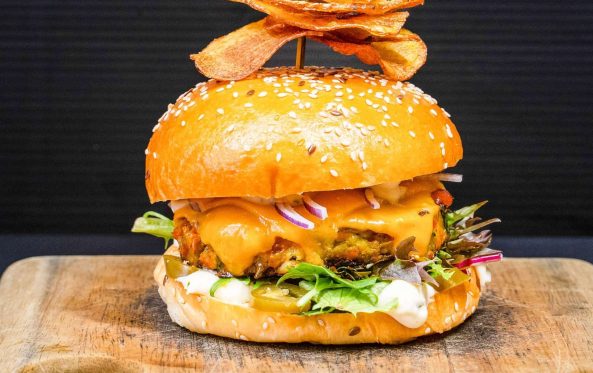 Veggie burger with melted cheese, salad and a crispy chip garnish