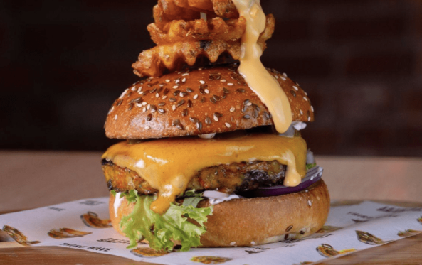 Veg burger with melted cheese, lettuce and a waffle fry skewer
