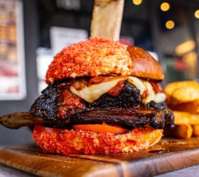 Flamin' Bonez Burger with a red chilli-crumbed bun and a rib bone skewer