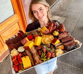 Guest holding the Meat Coma Platter tray at the restaurant entrance