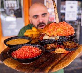 Guest holding the Flamin' Bonez Burger coated in red chilli crumbs