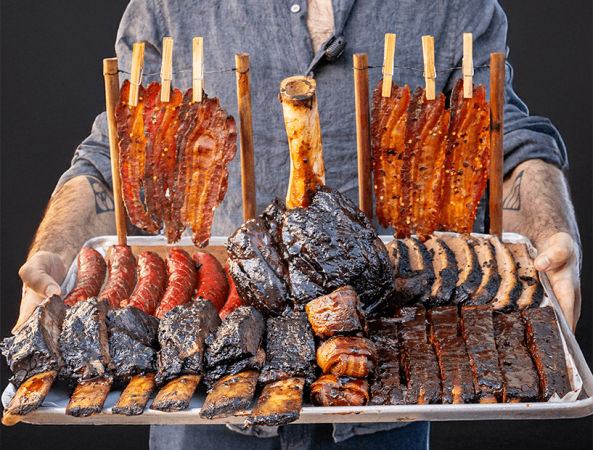 Guest holding a large BBQ platter with standing ribs and sausages