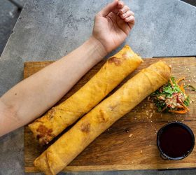 XXXL Spring Rolls on a board with herb garnish and dipping sauce