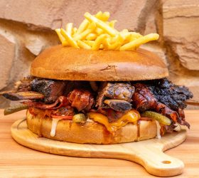 Almighty Burger loaded with brisket, cheese and fries on top of the bun