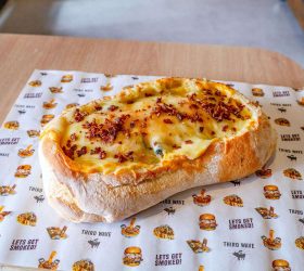 BBQ boat bread roll with melted cheese, on branded paper