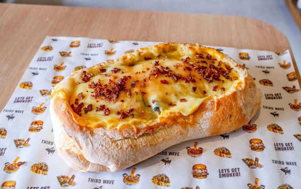 BBQ boat bread roll with melted cheese, on branded paper