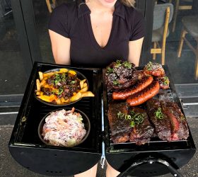 Guest holding the BBQ in a BBQ platter with ribs and loaded fries