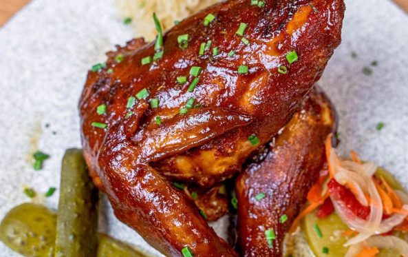 Smoked chicken quarter with pickles on a plate