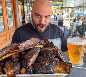Guest reacting with excitement to a huge platter of beef ribs and beer