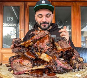 Guest holding a large stack of smoked pork ribs on a wooden board