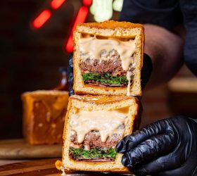 Chef holding the halved Cube Burger showing melted cheese and lettuce