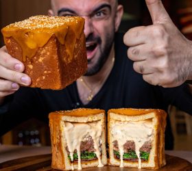 Person giving a thumbs-up holding the Cube Burger, cut open showing melted cheese