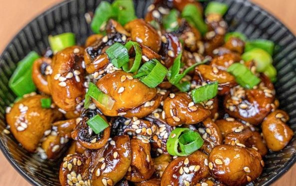 Glazed side dish of roasted vegetables with sesame seeds and spring onion