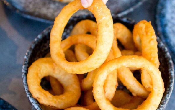 Hand stacking crispy onion rings into a bowl
