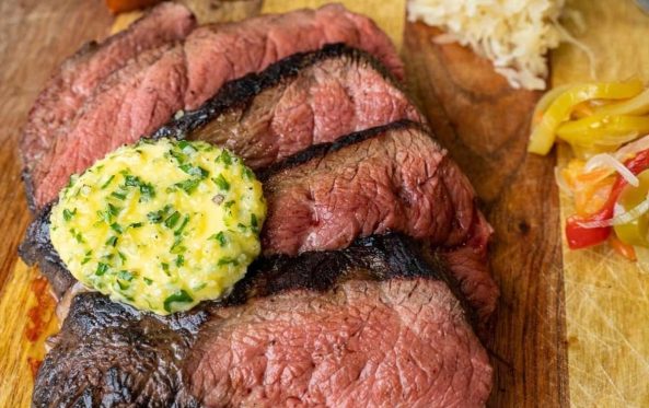 Sliced medium-rare steak with herb butter and pickled vegetables