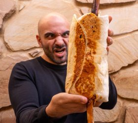 Guest holding the El Shanko Grande wrapped sandwich with a bone handle