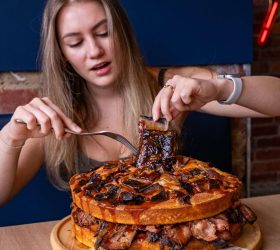 Diner cutting into a giant BBQ gigacake stack topped with a rib