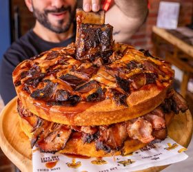 Giant stack of pancakes layered with ribs and bacon