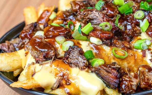 Brisket loaded fries with cheese sauce and spring onion in a bowl