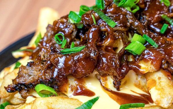 Loaded fries with a dark sauce and spring onion