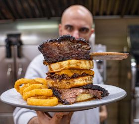 Beefy Mega Stack burger tower topped with a brisket rib and onion rings
