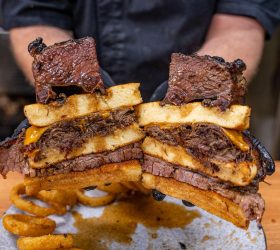 Chef holding two halves of the Beefy Mega Stack showing brisket and cheese