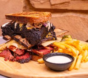 Reuben on Steroids sandwich stacked with meat and slaw, served with fries