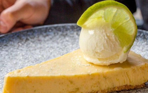 Wedge of citrus pie topped with ice cream and a lime wheel garnish