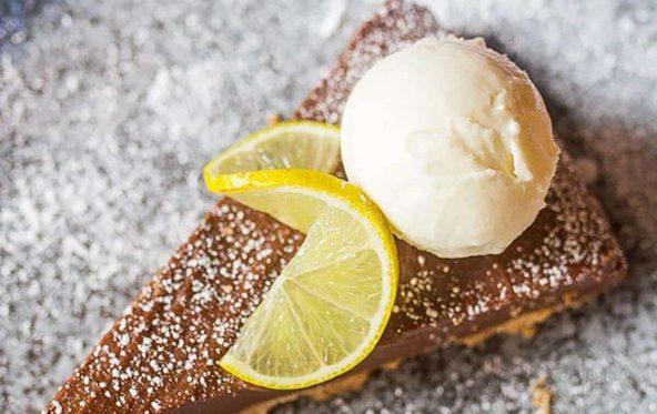 Slice of chocolate tart with a lime wheel garnish and a scoop of ice cream